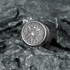 Silver symbolic stainless steel compass ring on a textured stone surface
