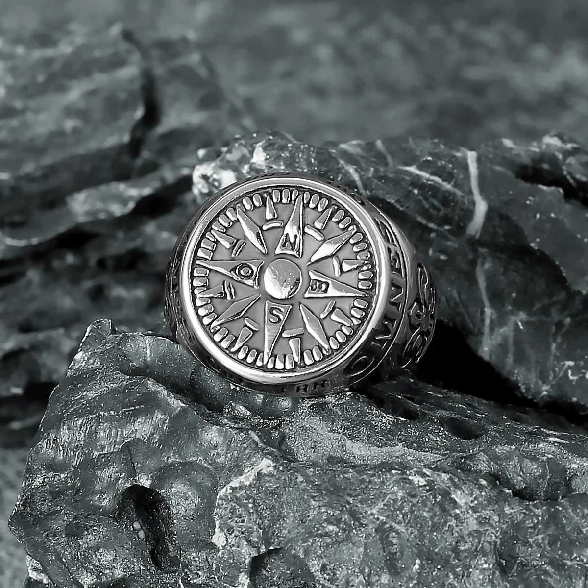 Silver symbolic stainless steel compass ring on a textured stone surface