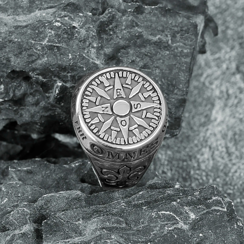 Silver stainless steel compass ring on a textured stone surface