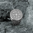 Silver stainless steel compass ring on a textured stone surface