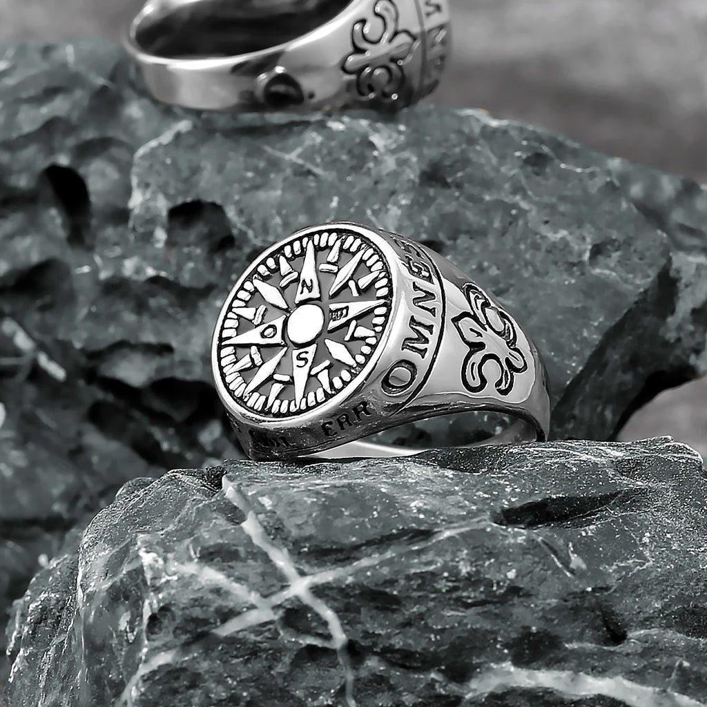 Silver ring with compass design on a textured stone surface