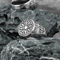 Silver ring with compass design on a textured stone surface