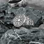 Silver ring with compass design on a textured stone surface