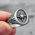 Silver ring with star design held by a hand against a blurred background