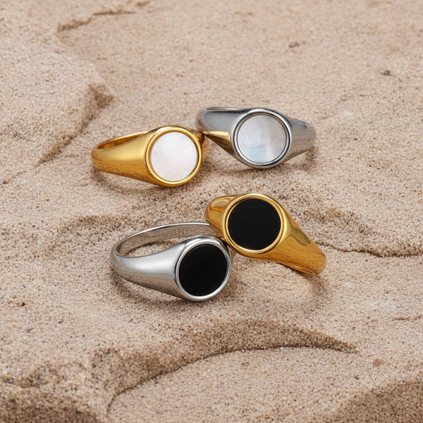 Four rings with different colored shell like surfaces on a sandy surface