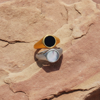 Two rings, one gold and one silver, on a textured sandstone surface