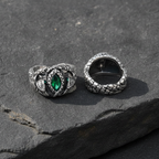 Two silver rings with green gemstones on a dark stone surface