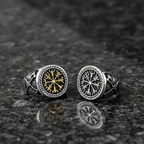 Two silver Viking signet rings with a intricate Vegvisir design on a dark grey granite stone surface