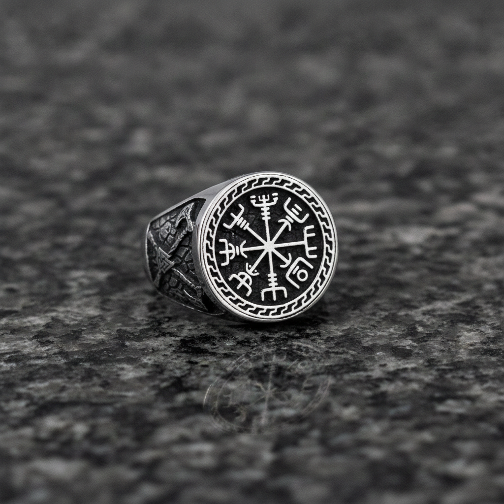 A silver Viking signet ring with a intricate Vegvisir design on a dark grey granite stone surface