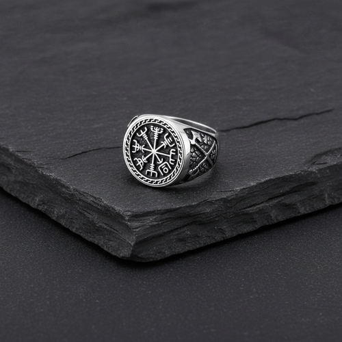 A silver Viking signet ring with a intricate Vegvisir design on a charcoal coloured stone surface