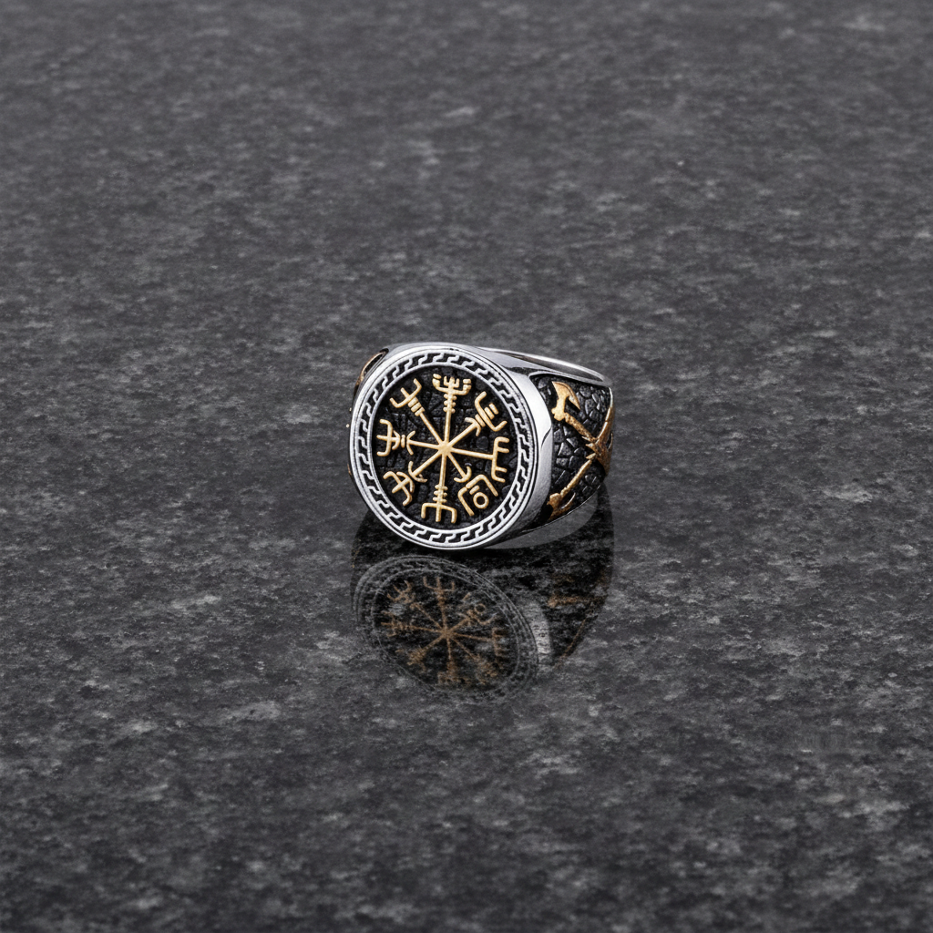 A silver and gold Viking signet ring with a intricate Vegvisir design on a dark grey granite stone surface