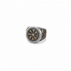 A silver and gold Viking signet ring with a intricate Vegvisir design on a dark grey granite stone surface