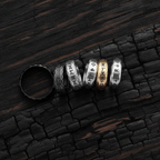 Set of silver and gold rings with engraved Viking designs on a dark wooden surface