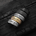 Viking and runic styled rings with engraved text on a dark wooden surface
