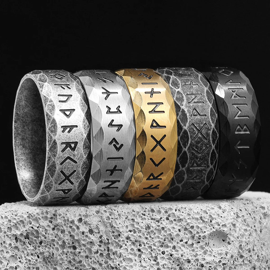 Set of five rings with engraved Viking runic symbols on a textured surface