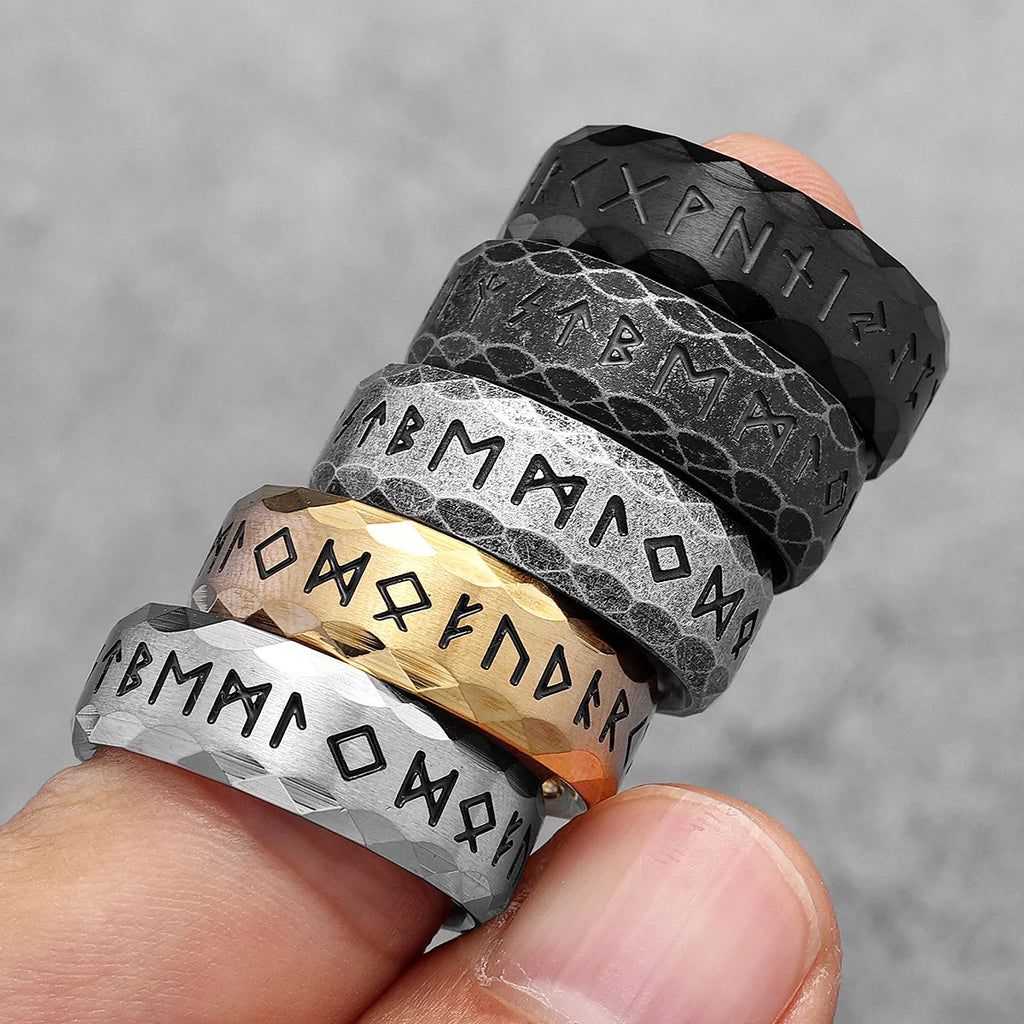 Stack of Nordic rings with engraved text on a finger against a grey background