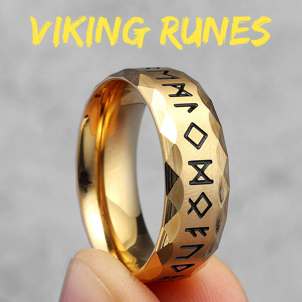 Gold ring with Viking runes held by a hand against a grey background