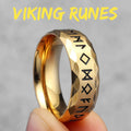 Gold ring with Viking runes held by a hand against a grey background