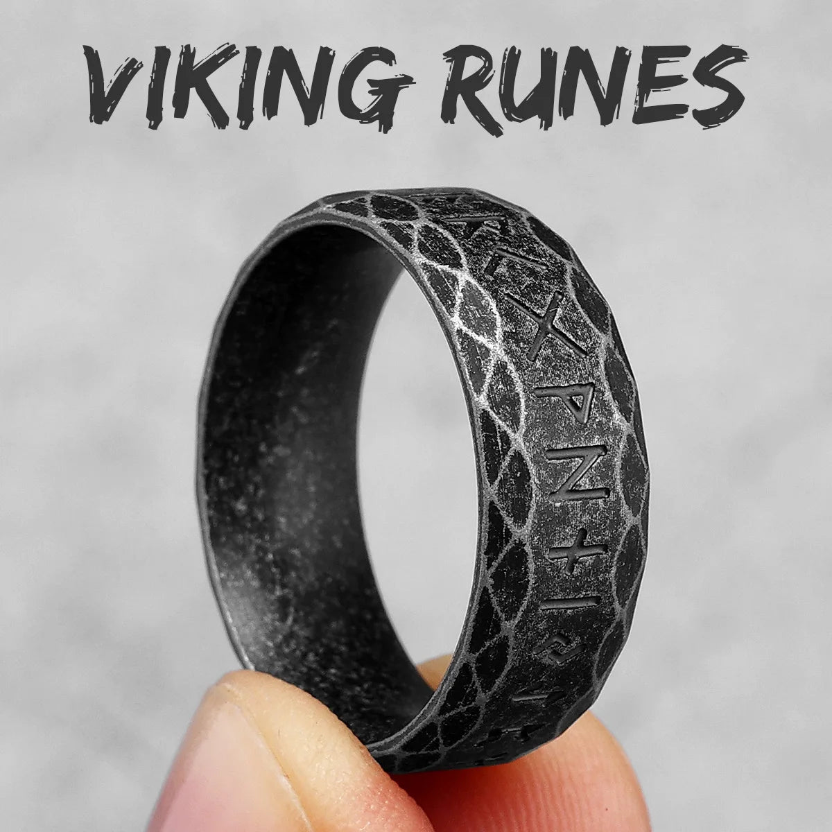 Vintage Black ring with Viking runes held by a hand against a grey background