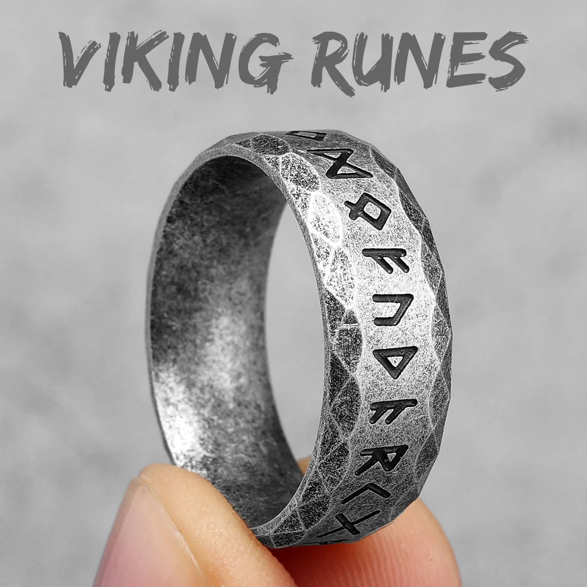 Vintage Silver ring with Viking runes held by a hand against a gray background